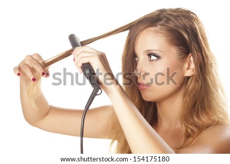 serious beautiful girl straightens her hair using hair straightening irons