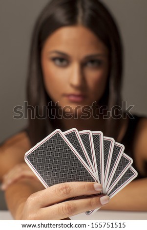 beautiful attractive girl holding poker cards and posing with a blank expression