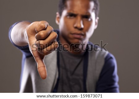 scowling dark young man showing thumb down