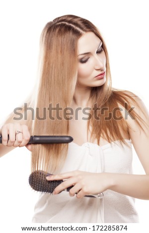 redheaded girl straightens the hair using a hair straightener and brush