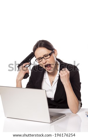 Desperate business woman with a laptop on the table, holding a gun to her head