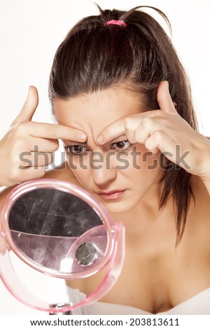 worried beautiful young woman watching her wrinkles on her forehead