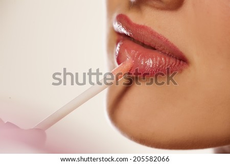 woman\'s lips and lip gloss applying