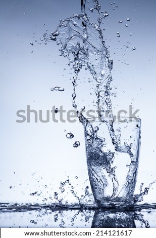 Water flows into the glass with splashes