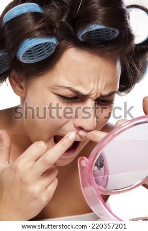 young woman with curlers squeezing pimple on her mustache