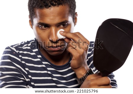 dark-skinned young man cleanse his face with cotton pad