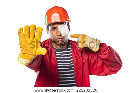 sad dark-skinned worker with helmet and injured eye showing stop hand