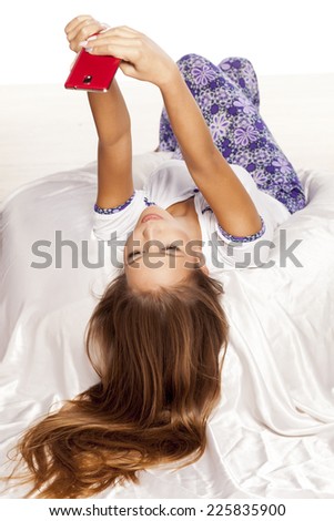 young woman with long hair lying on the bed and make a selfie