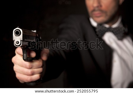 handsome man in a suit aim with a gun