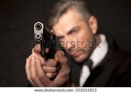 handsome man in a suit aim with a gun
