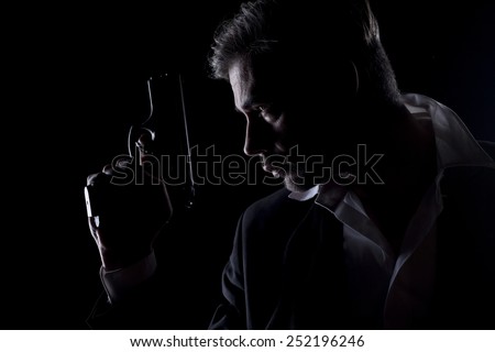 Profile of men's silhouette in the dark with a gun in his hand