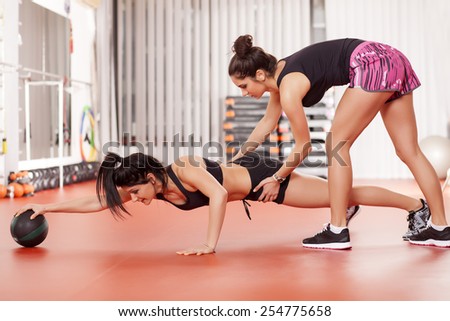 pretty young woman doing exercises with a medicine ball and instructor