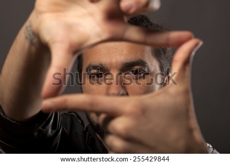 young man looking through fingers frame