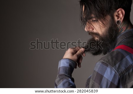 a young man with a beard and mustache touching his beard
