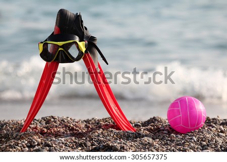plastic ball, flippers and mask for diving on the pebbly shore