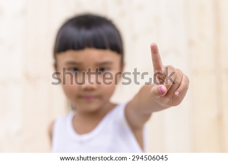 Kid with hand pose and blur face on wood wall background