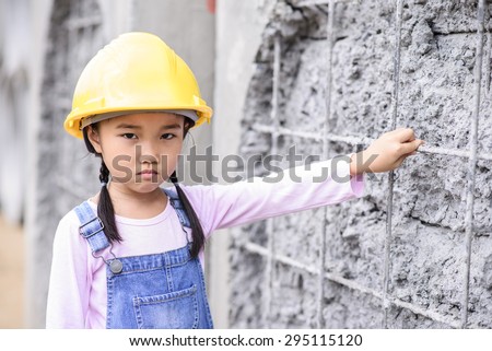 Kid civil engineer inspecting wire mesh on huge concrete pipe wall with bad mood