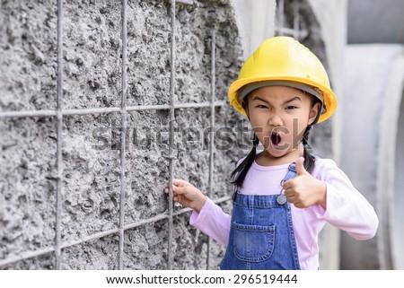 Kid civil engineer inspecting wire mesh on huge concrete pipe wall with thumb up