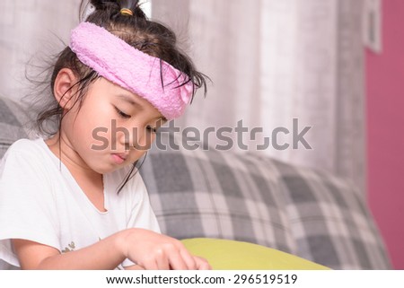 Kid with sick mood with pink towel cold pack on her head