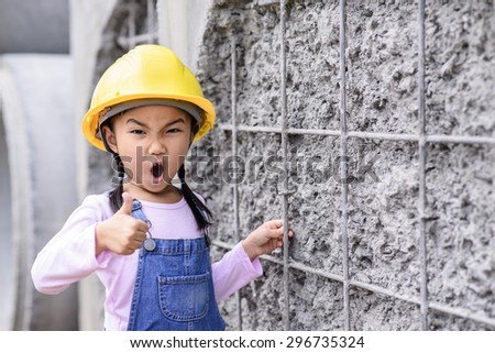 Kid civil engineer inspecting wire mesh on huge concrete pipe wall with blur thumb up