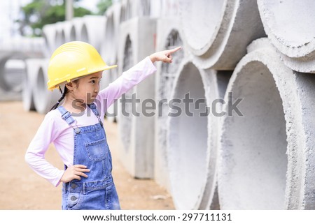 Kid civil engineer inspecting the huge concrete pipe and point to it