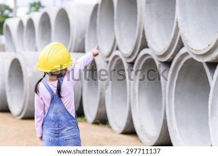 Kid civil engineer inspecting  huge concrete pipe and point to it