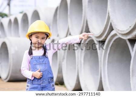 Kid civil engineer inspecting  huge concrete pipe and point to