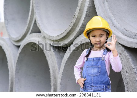 Kid civil engineer inspecting  huge concrete pipe ok with that and shown symbol