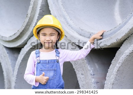 Kid civil engineer inspecting huge concrete pipe and make a thumb up