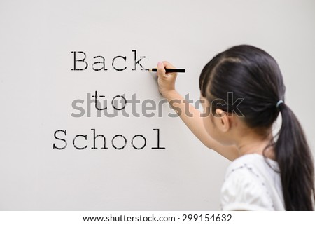 Kid write black color back to school on wall with blur face