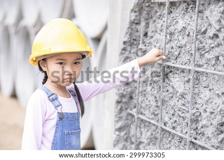 Kid civil engineer inspecting wire mesh on huge concrete pipe wall with bored mood