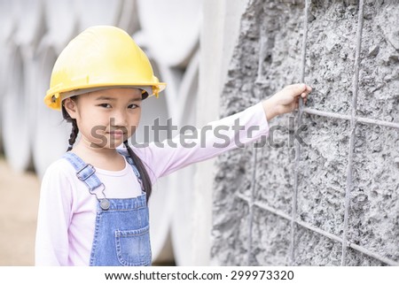Kid civil engineer inspecting wire mesh on huge concrete pipe wall with smile face