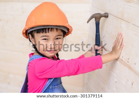 Kid engineer with carpenter work hammer on wood wall and smile