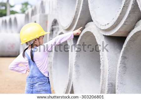 Kid civil engineer inspecting  huge concrete pipe and point to it
