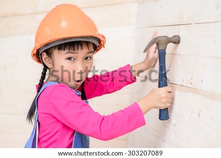 Kid engineer with carpenter work hammer on wood wall