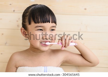 Little girl take a bath and brush teeth on wood wall background