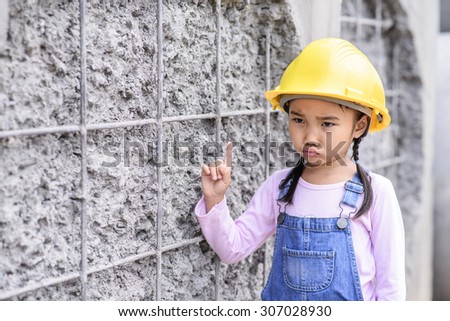 Kid civil engineer inspecting wire mesh on huge concrete pipe wall with worry mood