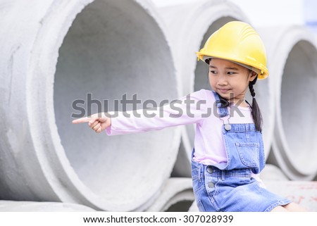 Kid civil engineer inspecting  huge concrete pipe and point to