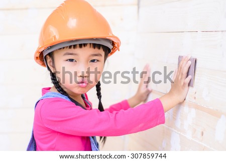 Little girl with carpenter work talent with sanding on wood
