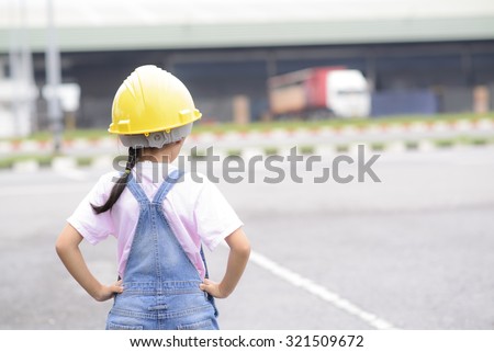 Little Asian girl inspecting on logistic work; Working in warehouse; orange safety helmet; Soft tone