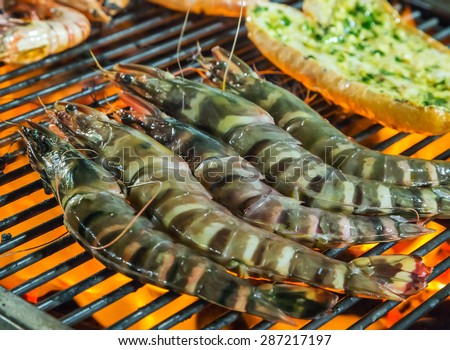 Grilled prawns on the grill seafood by fire and BBQ Flames. Restaurant Barbecue at the night market