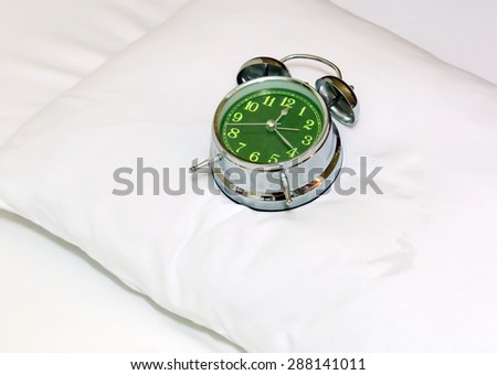 Alarm clock on bed sheets background