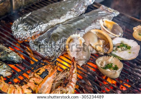 Grilled food seashells and mussel by fire and BBQ Flames.