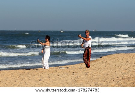 GOA, INDIA - FEB 10, 2014: European women are engaged in a dynamic yoga on Candolim beach. Goa beaches are very popular among the people practicing yoga