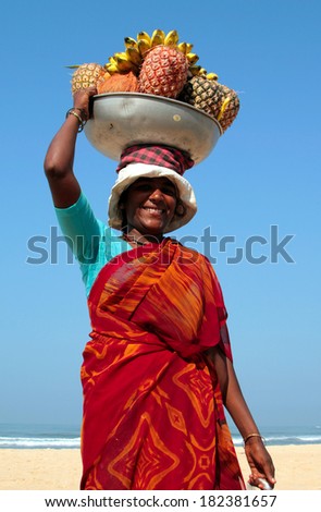 GOA, INDIA - FEB 18, 2008: Beautiful fruit vendor on the beach of Arabian sea. Indian women prefer to carry heavy things on their heads