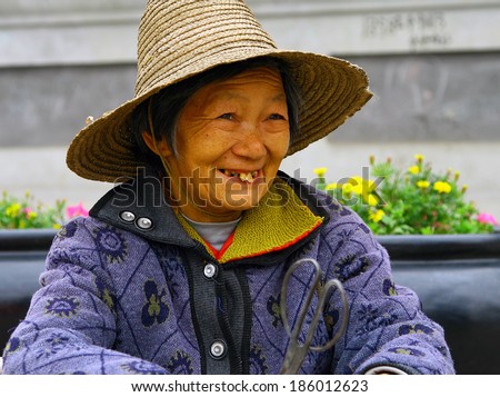 WUDANSHAN, CHINA - OCT 31, 2007: Smiling elderly chinese woman in a straw hat. In recent years, the average life expectancy in China has increased significantly and has already reached 72 years
