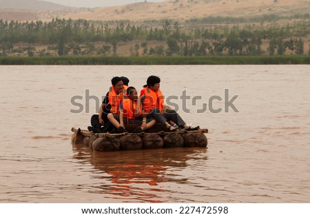 NINGXIA, CHINA - JUL 9, 2011: Tourists floating along the Yellow River (Huang He) on a sheepskin rafts. Balloons of these exotic rafts really made of sheep skin by locals. Shapotou Tourism area