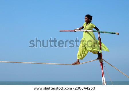 GOA, INDIA - FEB 12, 2008: Wandering tightrope walker playing on the beach. Small groups of buskers traveling along the coast and arrange free shows for tourists on the beach