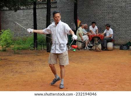 BEIJING, CHINA - JUL 17, 2011: Chinese man training with some kind of yo-yo in Jingshan park, not far from Forbidden City. Chinese yo-yo (kongzhong or hollow bell) was found during the Ming dynasty