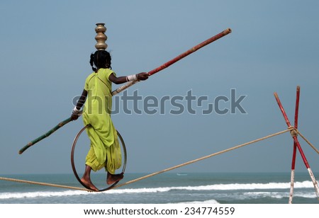GOA, INDIA - FEB 12, 2008: Wandering tightrope walker playing on the beach. Small groups of buskers traveling along the coast and arrange free shows for tourists on the beach